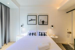 曼谷的住宿－UHU Bangkok，卧室配有一张白色大床,墙上挂有三张照片