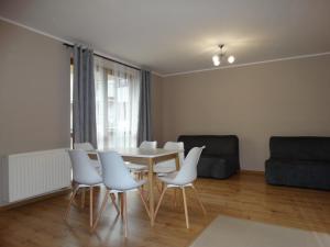 salon ze stołem i białymi krzesłami w obiekcie Apartamenty Miku w mieście Krynica Zdrój