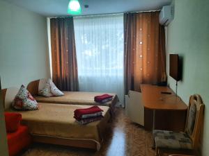 a bedroom with two beds and a desk and a window at Sanatoriy Zhosaly in Qarqaraly
