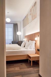 ein Schlafzimmer mit einem großen Bett mit weißen Kissen in der Unterkunft Hotel Walther v.d. Vogelweide Superior in Klausen