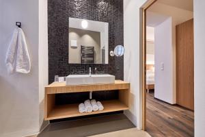ein Bad mit einem Waschbecken und einem Spiegel in der Unterkunft Hotel Walther v.d. Vogelweide Superior in Klausen