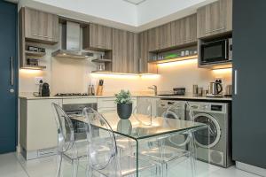 una cocina con mesa de cristal y sillas. en The Tyrwhitt Rosebank Apartments, en Johannesburgo