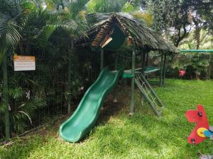 plac zabaw z zieloną zjeżdżalnią w trawie w obiekcie Esencia Hotel and Villas w mieście Playa Santa Teresa