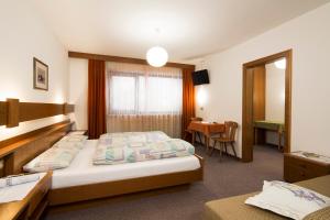 Habitación de hotel con 2 camas y mesa en Ciasa Iris, en Colfosco