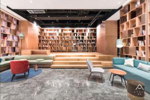 a library with a couch and chairs and bookshelves at Atour Hotel (Wuhan Qingshan Peace Park) in Wuhan