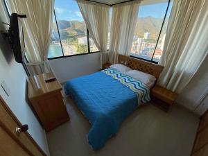 a bed in a room with large windows at Rivas Apartamentos Santa Marta in Santa Marta