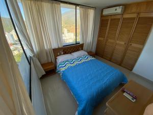 niewielka sypialnia z niebieskim łóżkiem i oknem w obiekcie Rivas Apartamentos Santa Marta w mieście Santa Marta