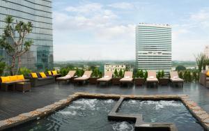 a rooftop patio with chairs and a pool on a building at Silverland Sakyo Hotel in Ho Chi Minh City