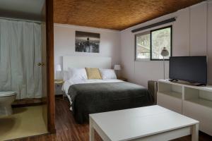 Un pequeño dormitorio con una cama y un televisor. en Camping Giralda, en Huelva 40 fotos más