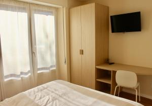 Dormitorio con cama, escritorio y TV en B&B Penak Mountain wellness, en Aprica