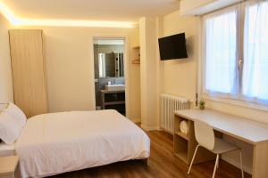 a bedroom with a bed and a desk and a window at B&B Penak Mountain wellness in Aprica