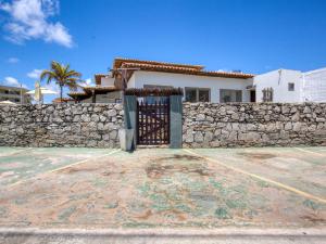 a house with a stone wall and a gate at Pousada Coqueiral in Maceió