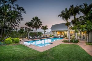 a backyard with a swimming pool and palm trees at Loerie's Call Guesthouse in Nelspruit