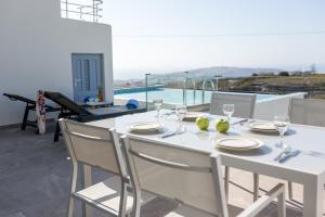 tavolo e sedie bianchi con vista sulla piscina di Luxe Maroussi Villas a Pyrgos