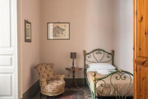 a bedroom with a bed and a chair at Palazzo Arcidiacono - luxury holidays in Catania