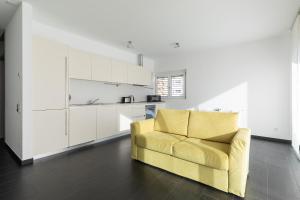 un sofá amarillo en una sala de estar con armarios blancos en Roggia Apartments by Quokka 360 - central flats with parking space, en Lugano
