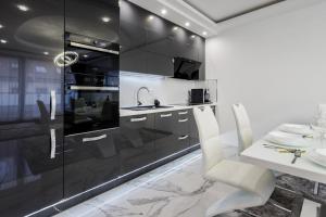 Kiraly 44 Luxury Apartment في بودابست: مطبخ مع دواليب سوداء وطاولة وكراسي بيضاء