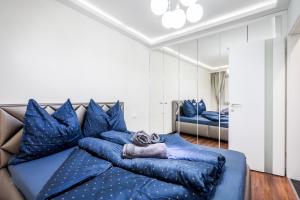 Kiraly 44 Luxury Apartment في بودابست: سرير أزرق كبير مع وسائد زرقاء في الغرفة