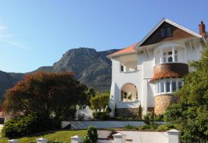 een wit huis met een berg op de achtergrond bij Abbey Manor Luxury Guesthouse in Kaapstad
