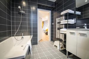 a bathroom with black tiles and a tub and a sink at Les apparts du marché in Obernai +40 photos
