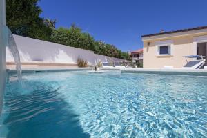 a swimming pool in front of a house at Charming villa Manuela with wonderful pool near the beach in Banjole
