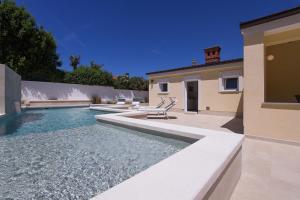 a house with a swimming pool in front of a house at Charming villa Manuela with wonderful pool near the beach in Banjole