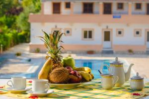 un bol de fruta sentado en una mesa con tazas de café en Takis Apartments en Sidari