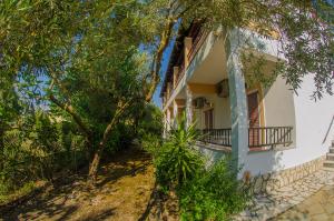 una casa bianca con un albero davanti di Takis Apartments a Sidari