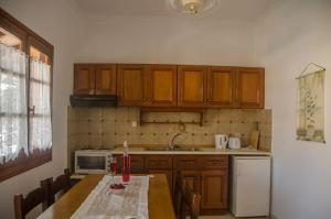 a kitchen with wooden cabinets and a table and a refrigerator at Takis Apartments in Sidari