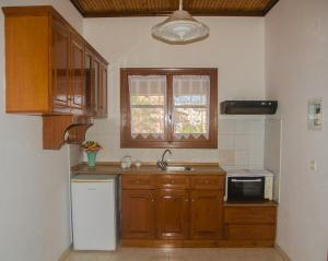a kitchen with wooden cabinets and a sink and a window at Takis Apartments in Sidari