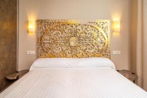 a bed with a white comforter and pillows at Apartamentos SEVILLA ESTE in Seville