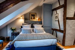 um quarto com uma cama grande e almofadas azuis e brancas em La Petite Folie em Honfleur