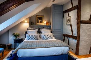 a bedroom with a large bed with blue and white pillows at La Petite Folie in Honfleur