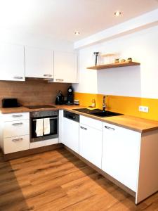 a kitchen with white cabinets and a wooden floor at db Apart in Finkenberg