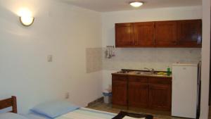 a kitchen with wooden cabinets and a sink and a refrigerator at Apartments Kuss in Novalja