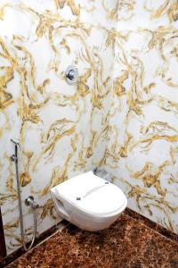 a white toilet in a bathroom with a marble wall at Hotel Nest N Rest - Mumbai in Mumbai