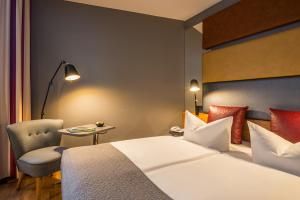ベルリンにあるMercure Hotel Berlin Zentrum Superiorのベッド、椅子、テーブルが備わるホテルルームです。