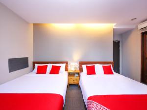 two beds in a room with red and white pillows at Super OYO 910 Hills Residence in Kuching