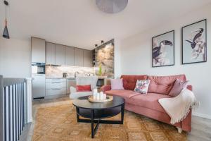 a living room with a pink couch and a table at Apartamenty Sun & Snow Residence II Jastrzębia Góra in Jastrzębia Góra