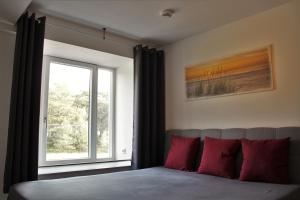 Schlafzimmer mit einem Fenster und einem Bett mit roten Kissen in der Unterkunft Bruchbude mit Meerblick in Binz