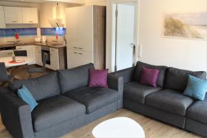 ein Wohnzimmer mit einem grauen Sofa und lila Kissen in der Unterkunft Bruchbude mit Meerblick in Binz