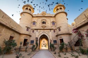 a large building with birds flying in the sky at WelcomHeritage Mohangarh Fort in Jaisalmer