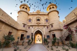 un gran edificio con aves volando en el cielo en WelcomHeritage Mohangarh Fort en Jaisalmer