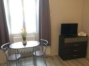 una mesa pequeña y sillas en una habitación con TV en Les Conches, Chambres d'Hôtes et Gite, en Thiviers