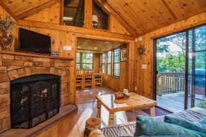 ein Wohnzimmer mit einem Kamin in einer Blockhütte in der Unterkunft Family Cabin on 6 Acres with Lake Access and Hot Tub! in Springfield