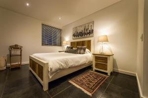 ein Schlafzimmer mit einem Bett und einem Tisch mit einer Lampe in der Unterkunft Club Mykonos Langebaan in Langebaan