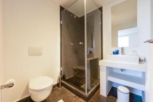 a bathroom with a shower and a toilet and a sink at Club Mykonos Langebaan in Langebaan
