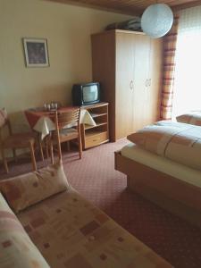 a hotel room with a bed and a table and a television at Gästehaus Steininger in Zwiesel