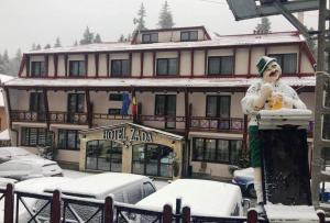 une statue d'une femme debout devant un bâtiment dans l'établissement Hotel Zada, à Predeal