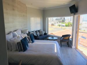 ein Schlafzimmer mit einem großen Bett und einem großen Fenster in der Unterkunft Gull on the Bay Boutique Guest House in Bloubergstrand